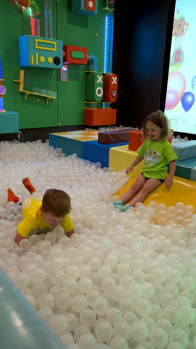 Two preschoolers playing in the white ball pit