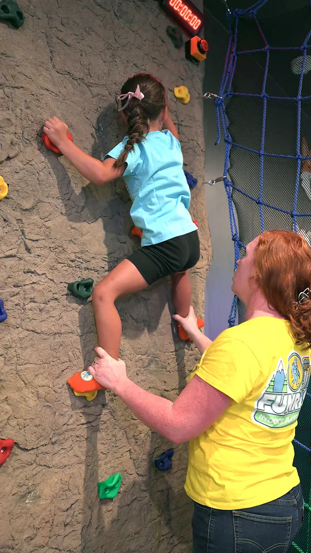 A preschooler climbing the rock wall