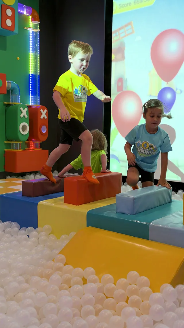 Kids jumping across foam blocks beside the ball pit