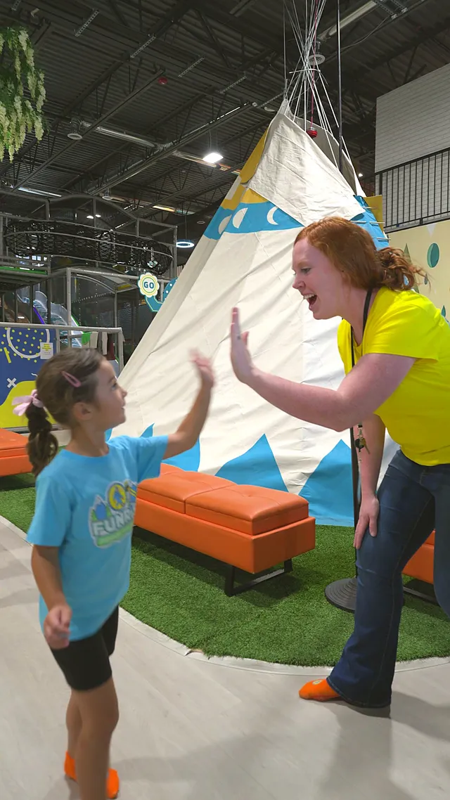 A teacher high-fiving a preschooler in front of the teepee