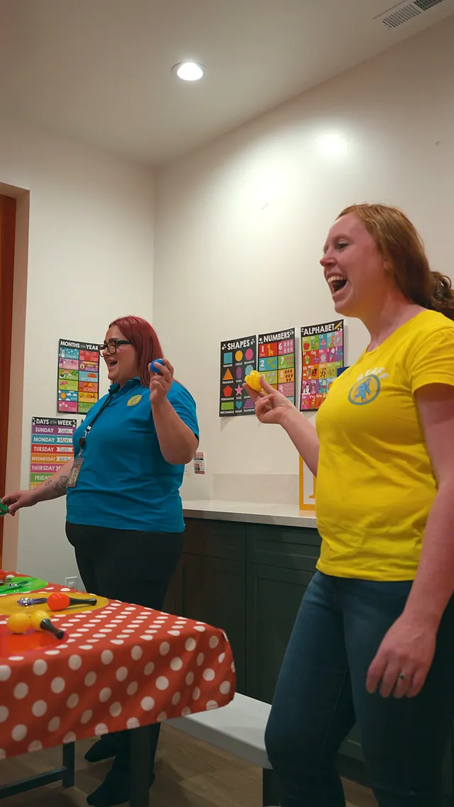 Two teachers laughing with the class at the sensory table